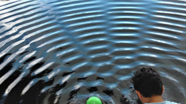 Water waves from two sources (one visible in green, the other hidden behind the presenter).  Circular waves interfere with regions of additional strength (bright lines) and areas where the waves cancel each other (dark bands).  The formation of the lines is the signature of the movement of the wave. 