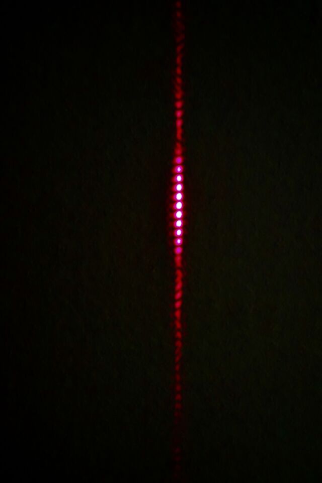 Laser light passing through the two horizontal slits produces the characteristic strips of quantum mechanics.