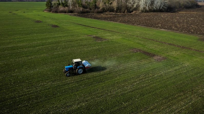 An aerial view shows a tractor spreading fertiliser on a wheat field near the village of Yakovlivka after it was hit by an aerial bombardment outside Kharkiv, as Russia's attack on Ukraine continues, April 5, 2022. REUTERS/Thomas Peter/File Photo