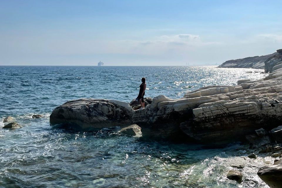 Портрет Олени, молодої росіянки, яка втекла зі своєї країни, стоїть на камені на пляжі.
